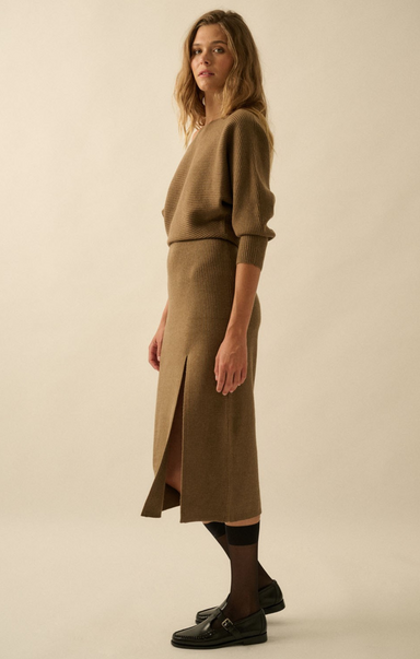 Woman wearing a brown sweater and skirt set on a beige background