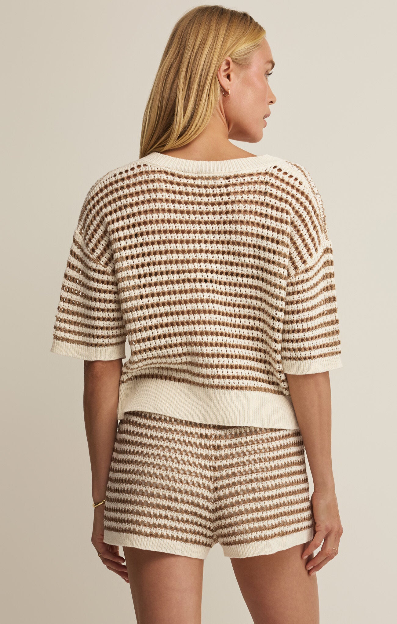 Woman wearing a matching striped outfit with a beige background