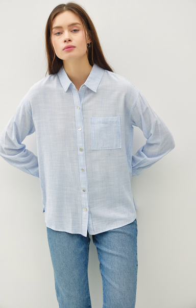 Woman wearing a light blue striped shirt and jeans against a white background