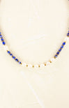 Necklace with blue and gold beads on a beige background