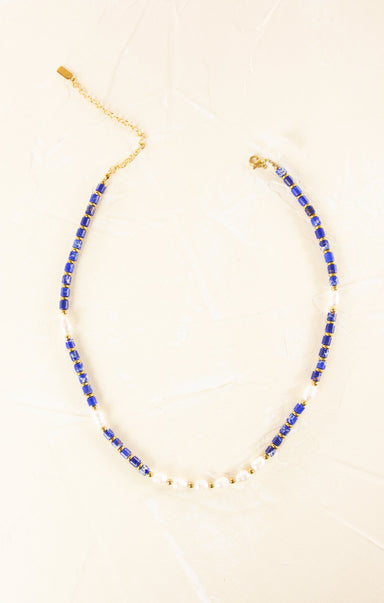 Necklace with blue beads and gold chain on a beige background