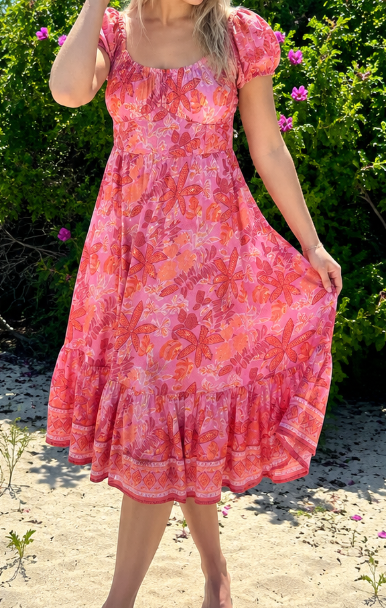 Woman wearing a pink floral dress standing outdoors with greenery in the background