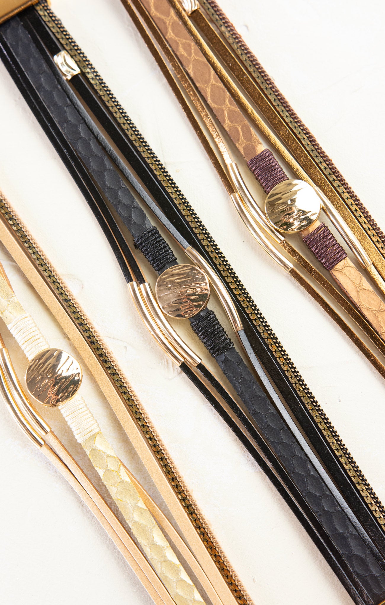 Three pairs of tweezers with gold and black handles on a white background