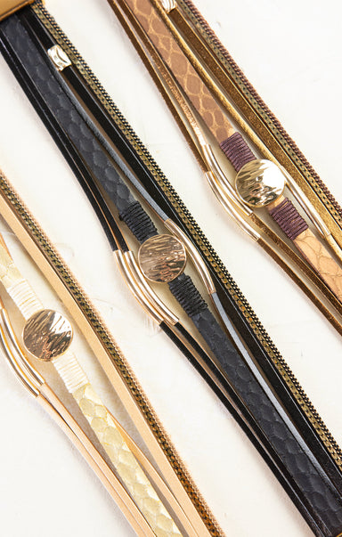 Three pairs of tweezers with gold and black handles on a white background