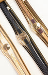 Three pairs of tweezers with gold and black handles on a white background