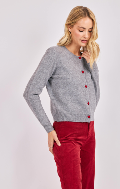 Woman wearing a gray sweater with red buttons and red pants on a white background