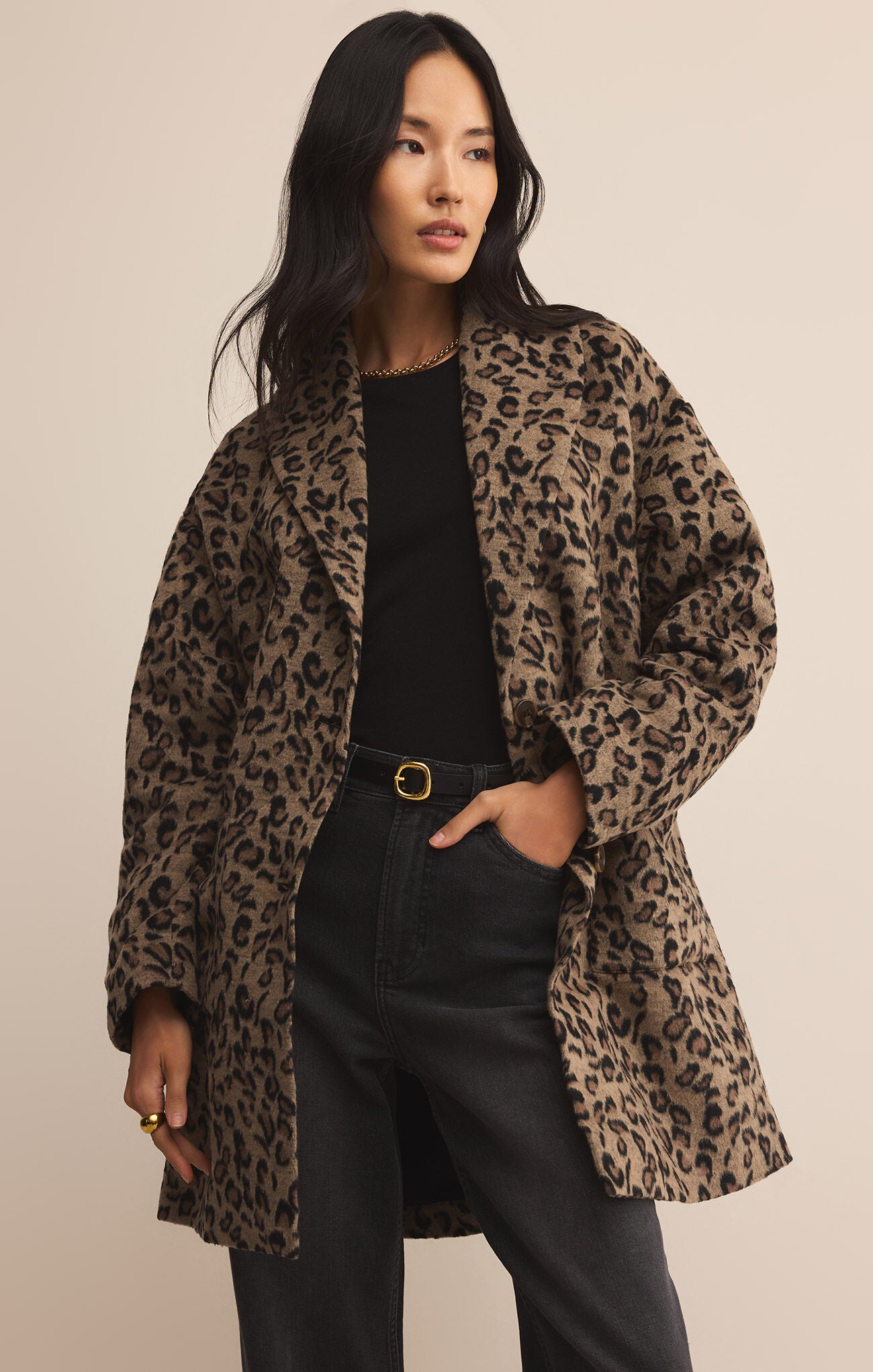 Woman wearing a leopard print coat against a beige background