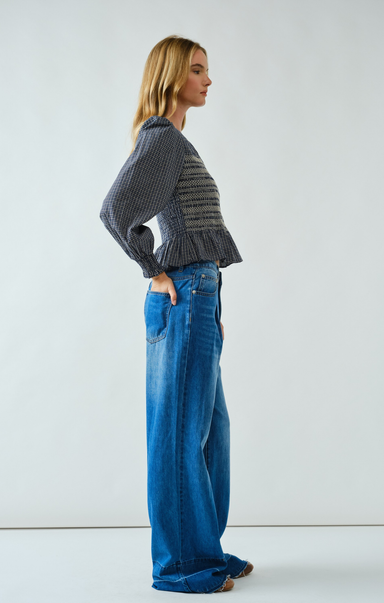Woman wearing a gray sweater and blue jeans against a white background