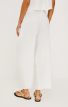 Person wearing white pants and sandals on a plain background