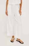 Person wearing white pants and sandals on a plain background