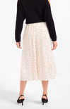 Person wearing a black top and white skirt with black polka dots on a white background