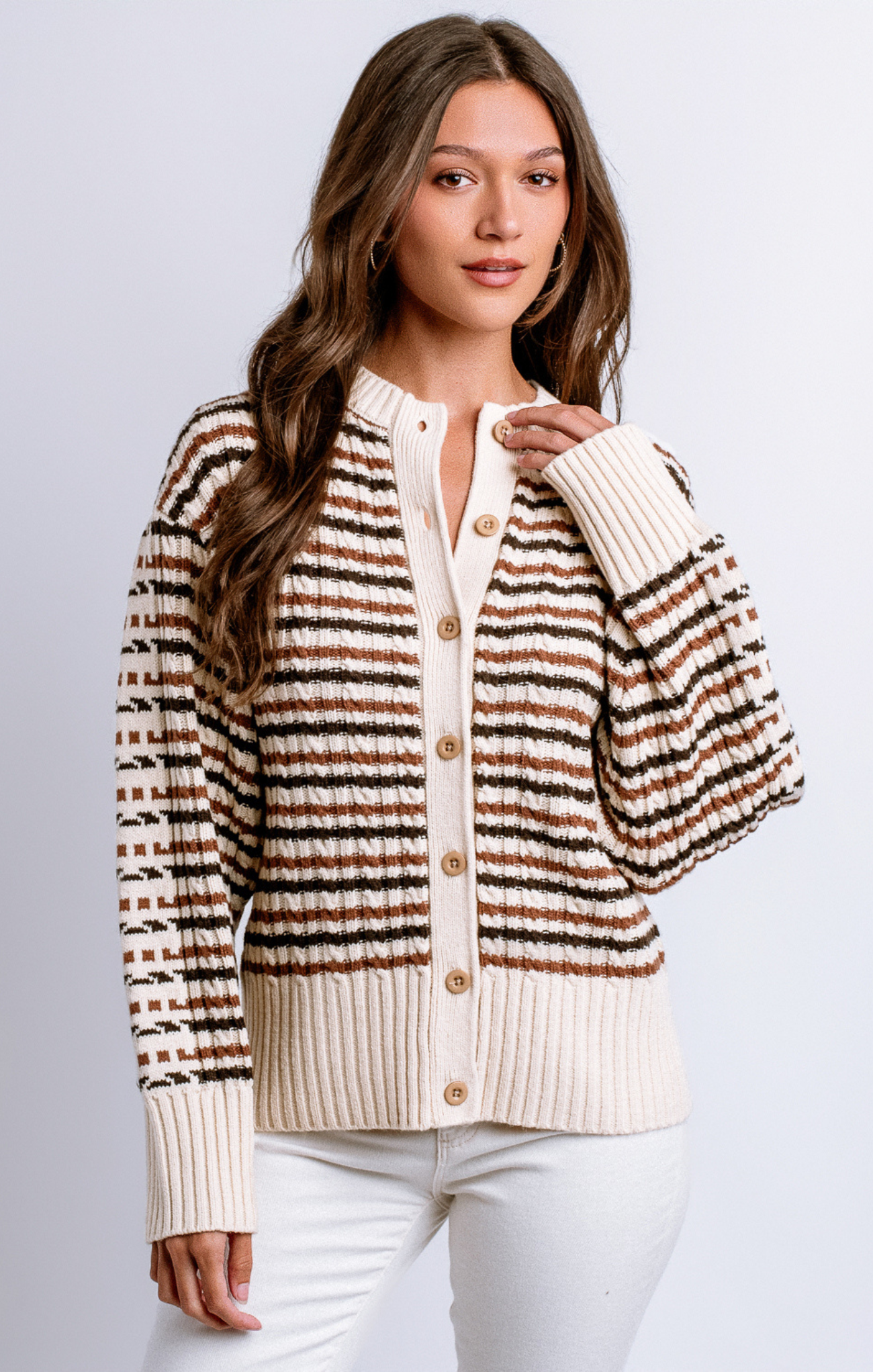 Woman wearing a striped cardigan over a white shirt on a light gray background