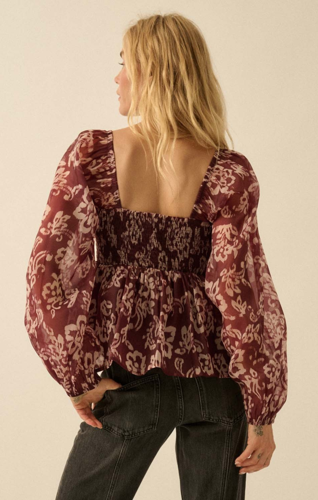 Woman wearing a burgundy floral blouse with a plain background