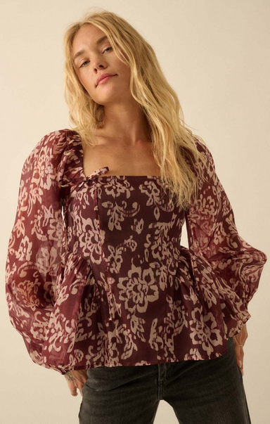 Woman wearing a patterned blouse against a plain background