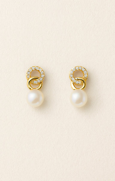 Pair of gold earrings with pearls on a beige background