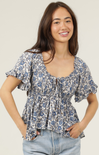 Woman wearing a floral blouse with ruffled sleeves on a plain background