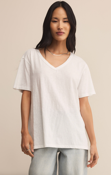 Woman wearing a white t-shirt and light blue jeans against a beige background