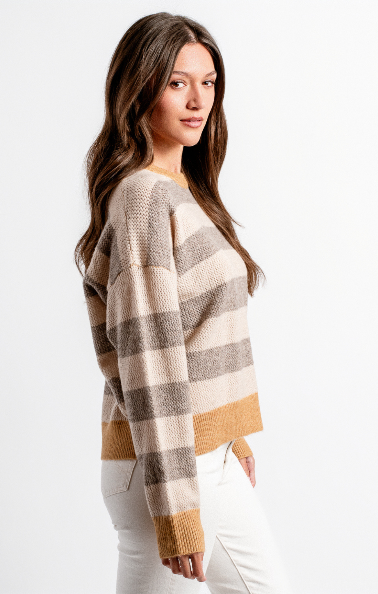 Woman wearing a plaid sweater with a neutral color palette on a white background