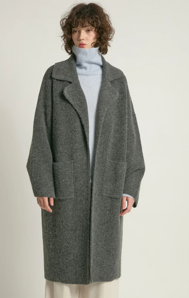 Person wearing a gray coat on a plain background