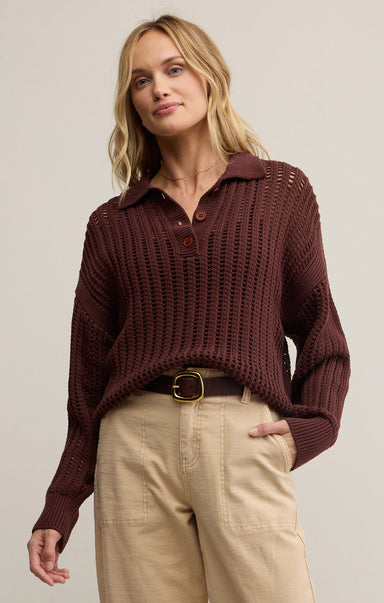 A woman wearing a brown collared long sleeve button front polo sweater with a relaxed fit, paired with beige pants.