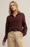 A woman wearing a brown collared long sleeve button front polo sweater with a relaxed fit, paired with beige pants.