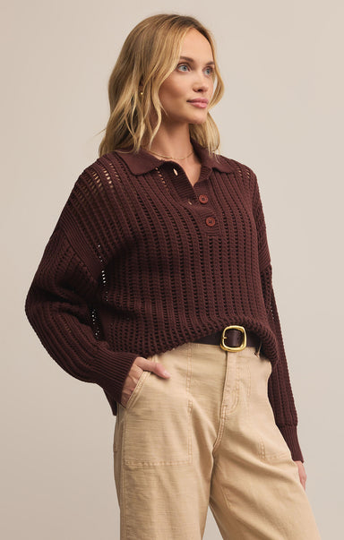 A woman wearing a brown collared long sleeve button front polo sweater with a relaxed fit, paired with beige pants.