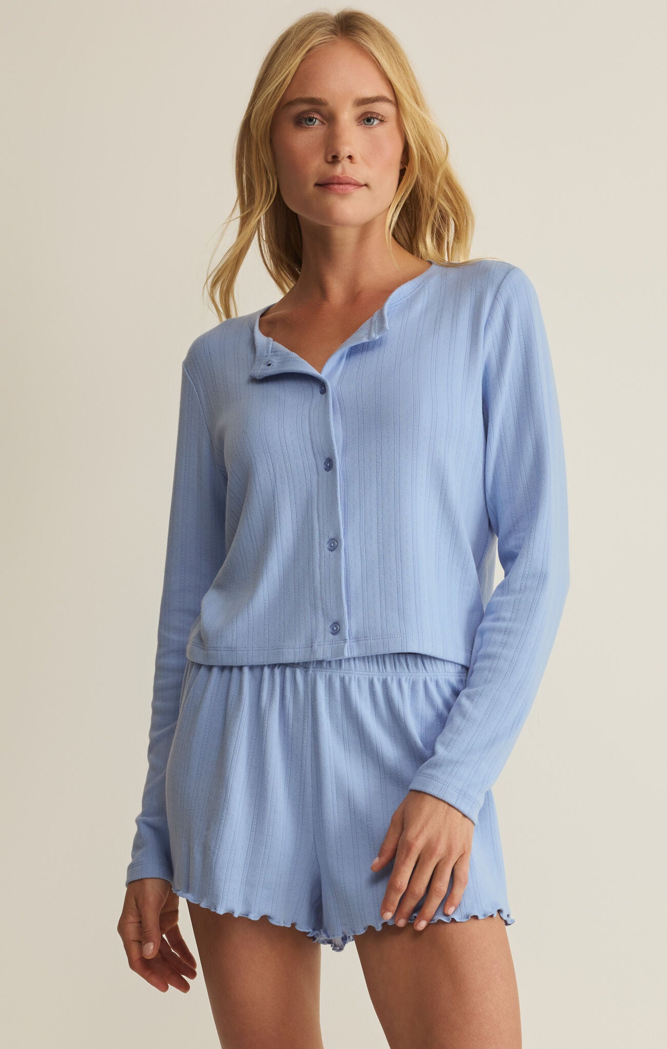 Woman wearing a light blue pajama set against a beige background