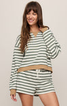 Woman wearing a green and white striped outfit with a beige waistband on a plain background