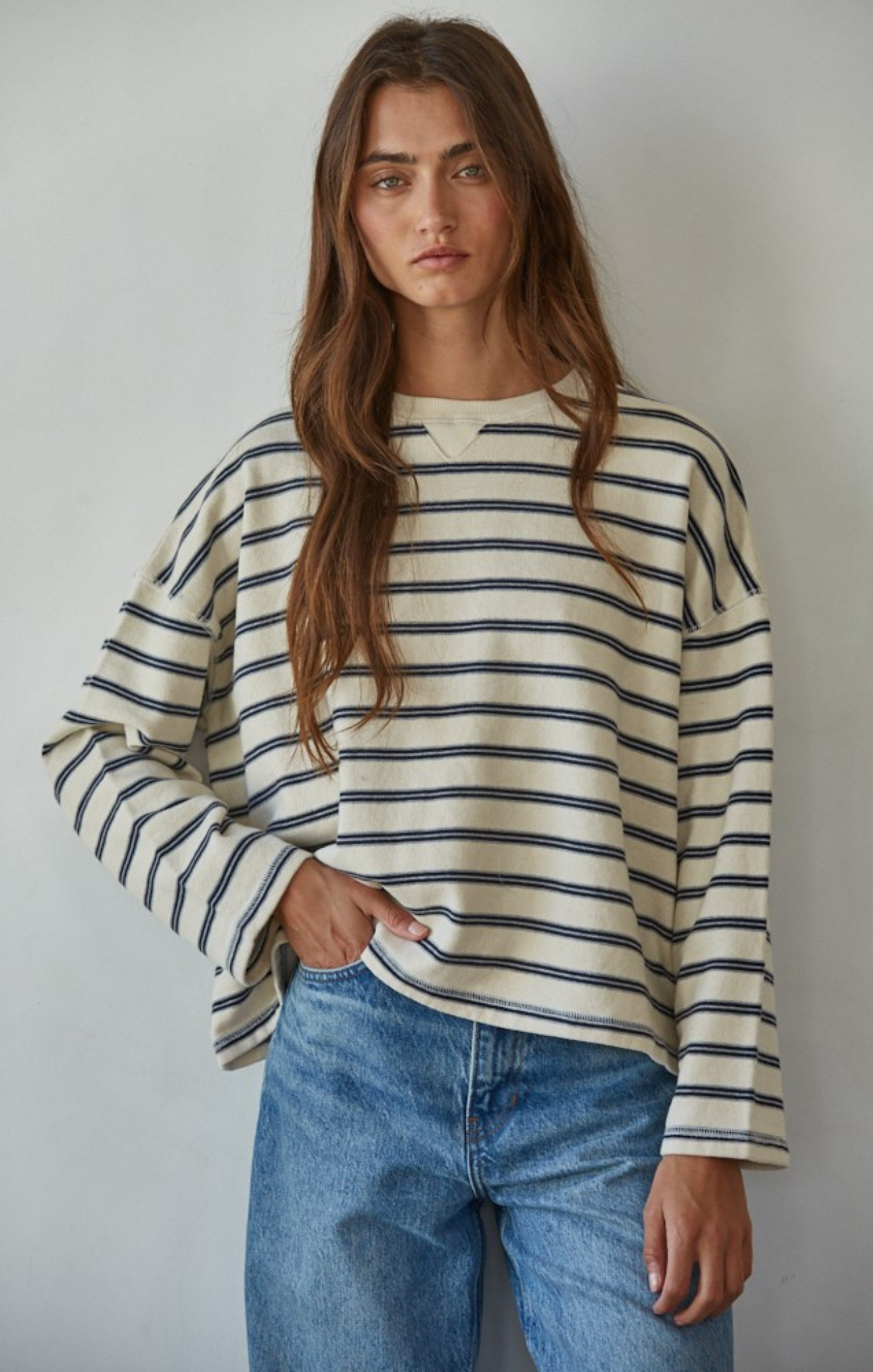 Person wearing a striped sweater and jeans against a plain background