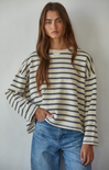 Person wearing a striped sweater and jeans against a plain background