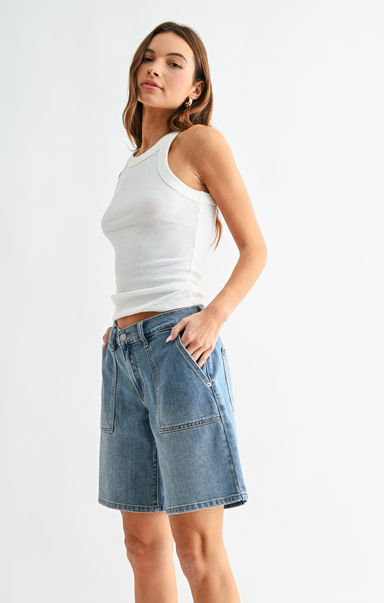 Woman wearing a white tank top and denim shorts on a white background