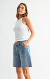 Woman wearing a white tank top and denim shorts on a white background