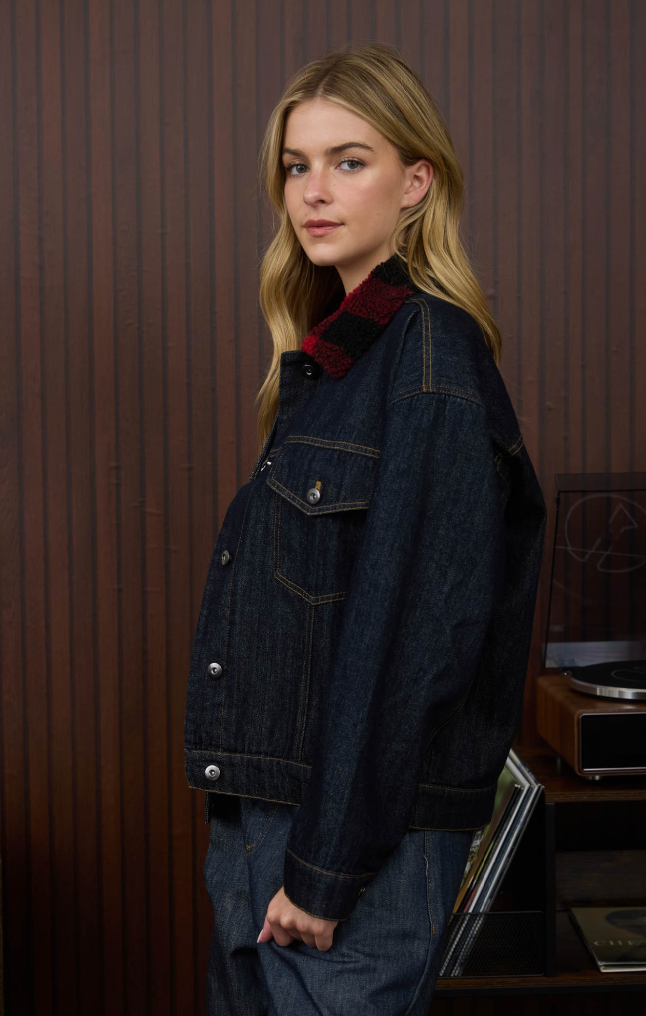 Person wearing a dark denim jacket in a room with wooden paneling