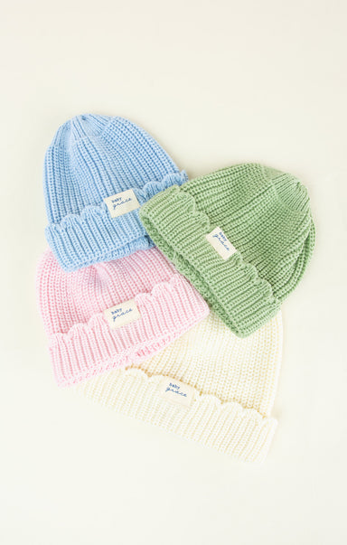 Four pastel-colored knit hats arranged in a row on a light background