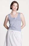 Woman wearing a striped tank top and white pants on a plain background