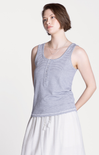Woman wearing a striped tank top and white pants on a plain background