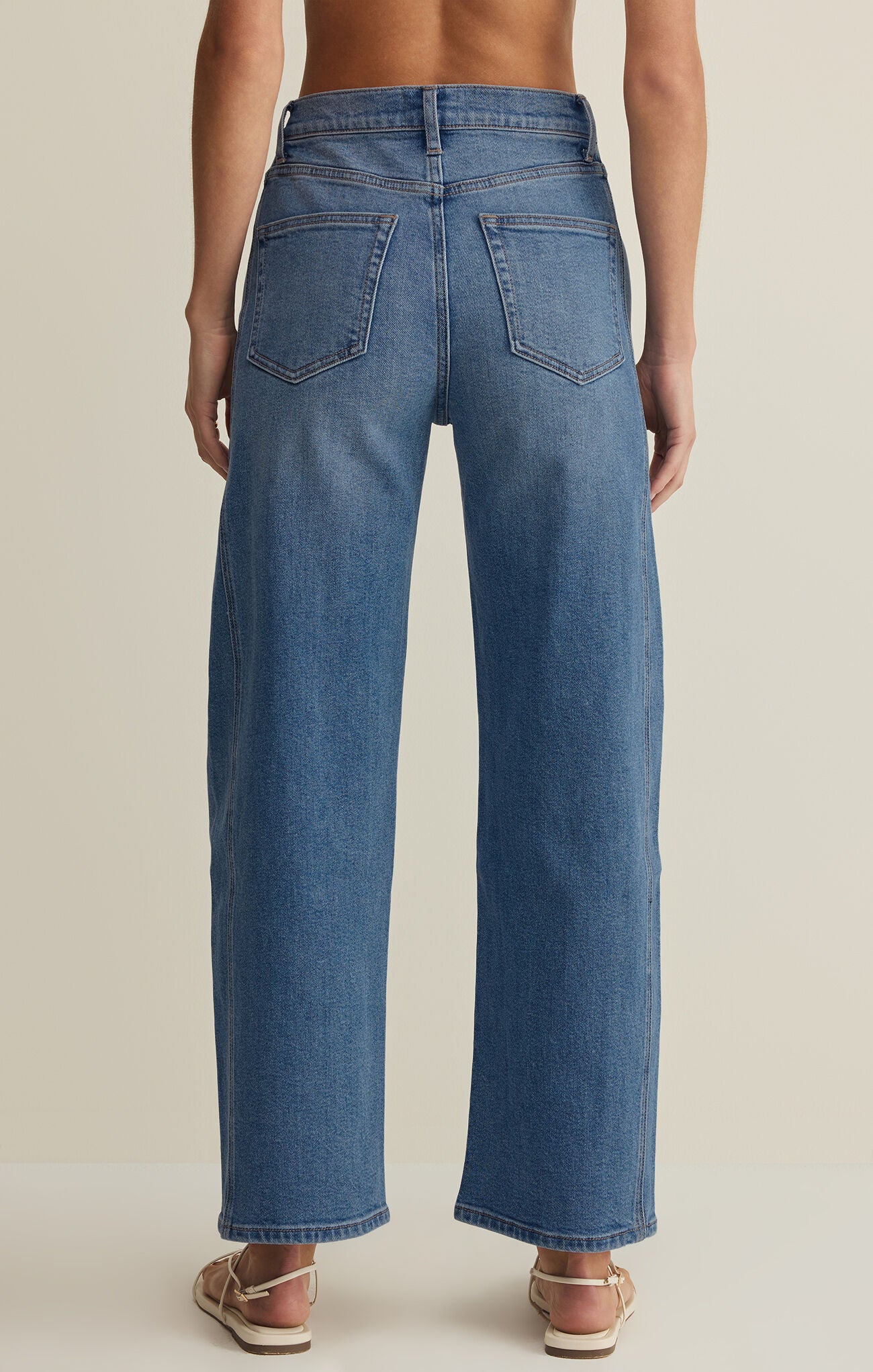 Blue jeans worn by a person on a beige background