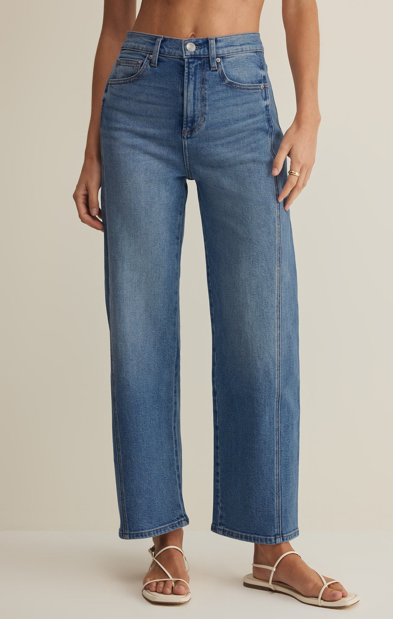 Person wearing blue jeans on a neutral background