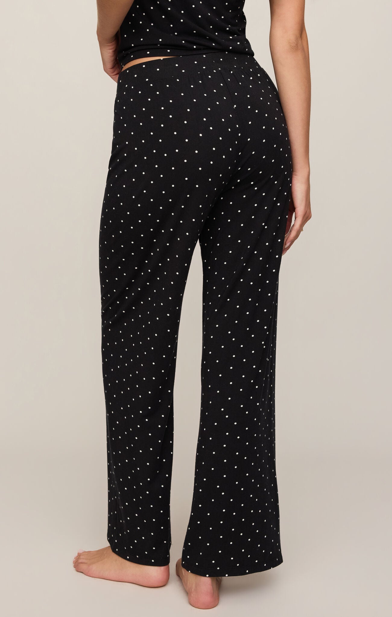 Black pants with white star pattern worn by a person on a beige background