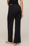 Black pants with white star pattern worn by a person on a beige background