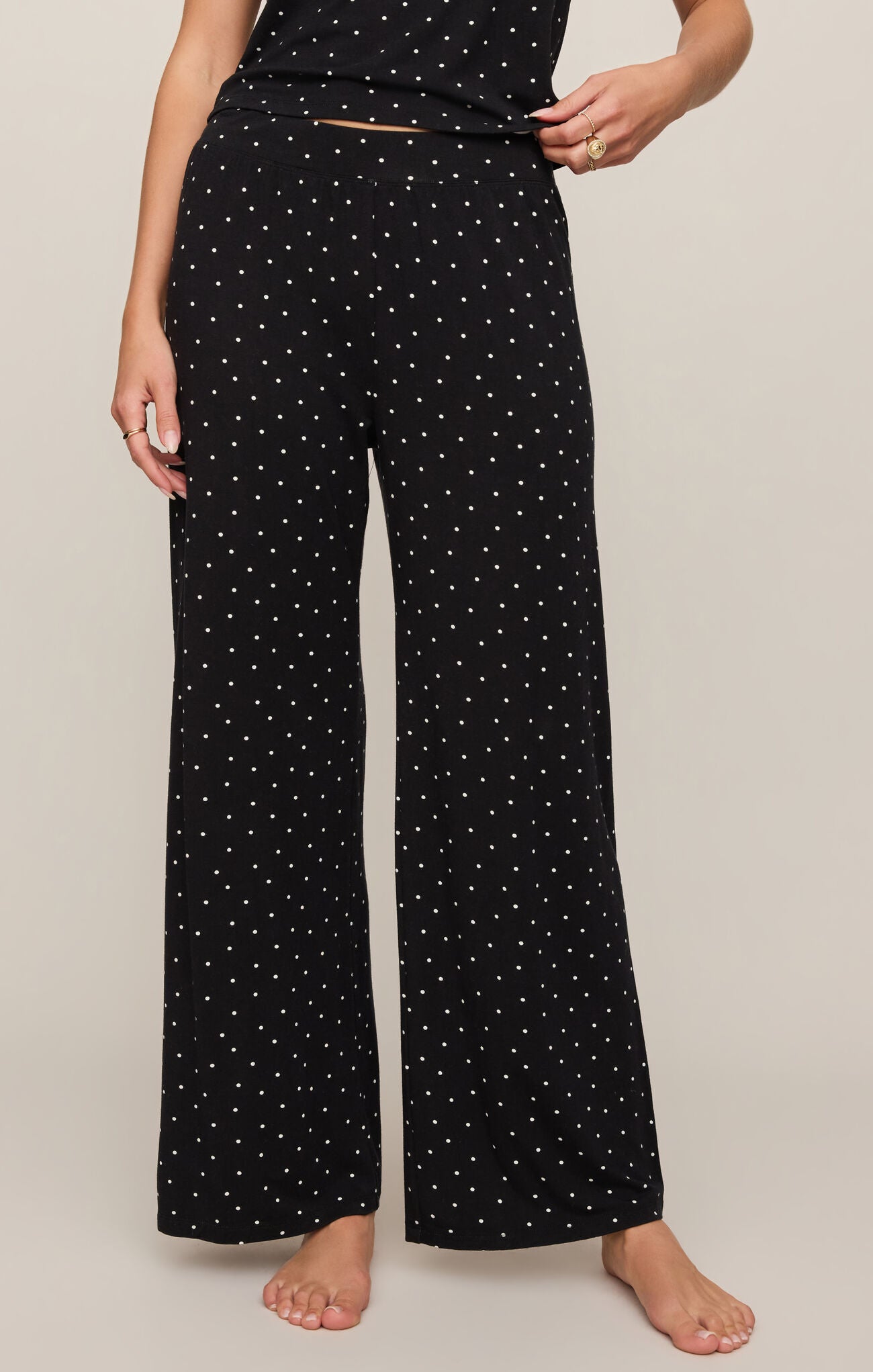 Person wearing black wide-leg pants with white star pattern on a plain background