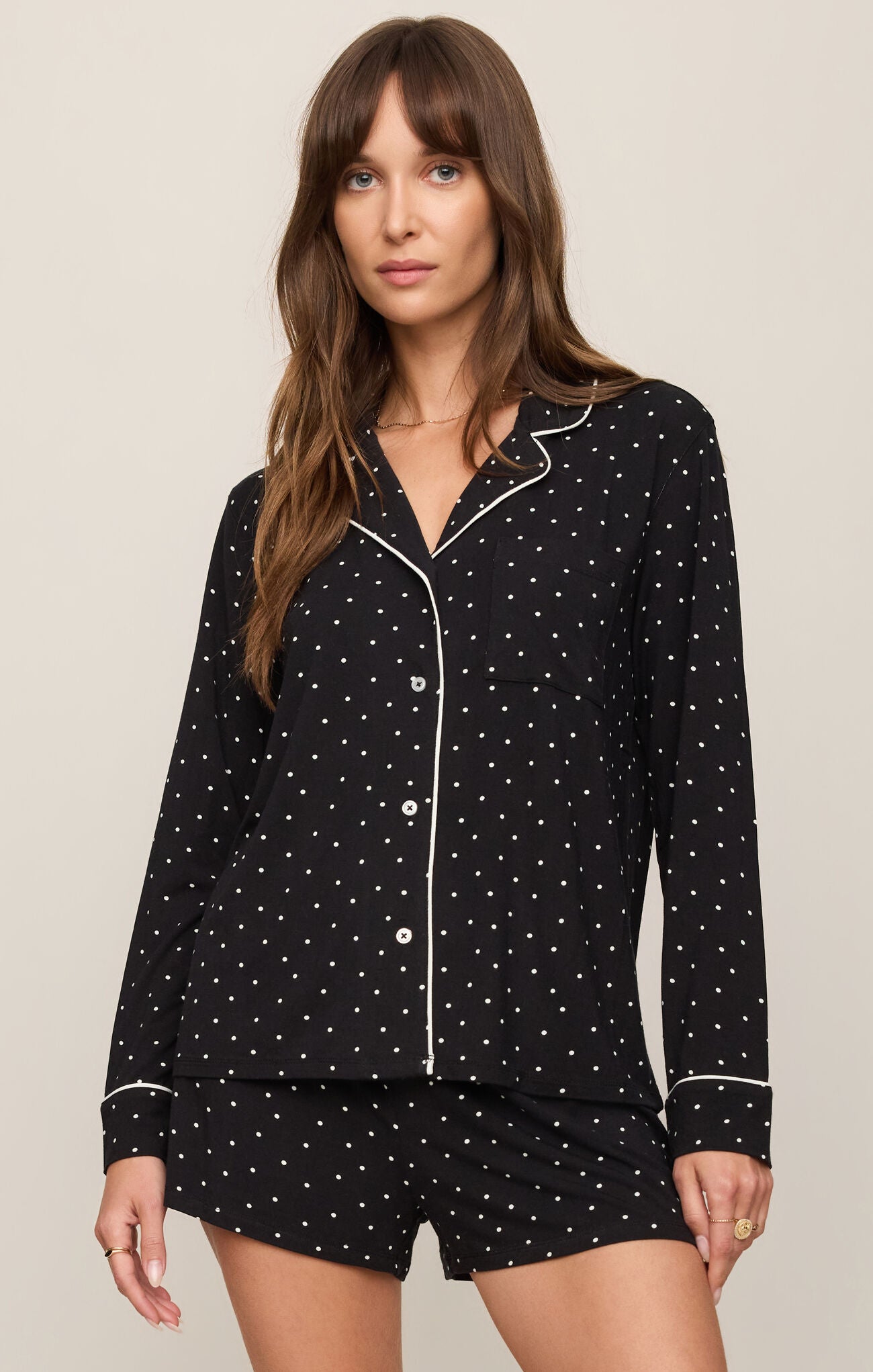 Woman wearing a black polka dot pajama set on a beige background