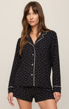 Woman wearing a black polka dot pajama set on a beige background