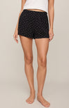 Person wearing black shorts with white polka dots on a beige background