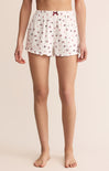 White pajama shorts with a floral pattern worn by a person on a beige background