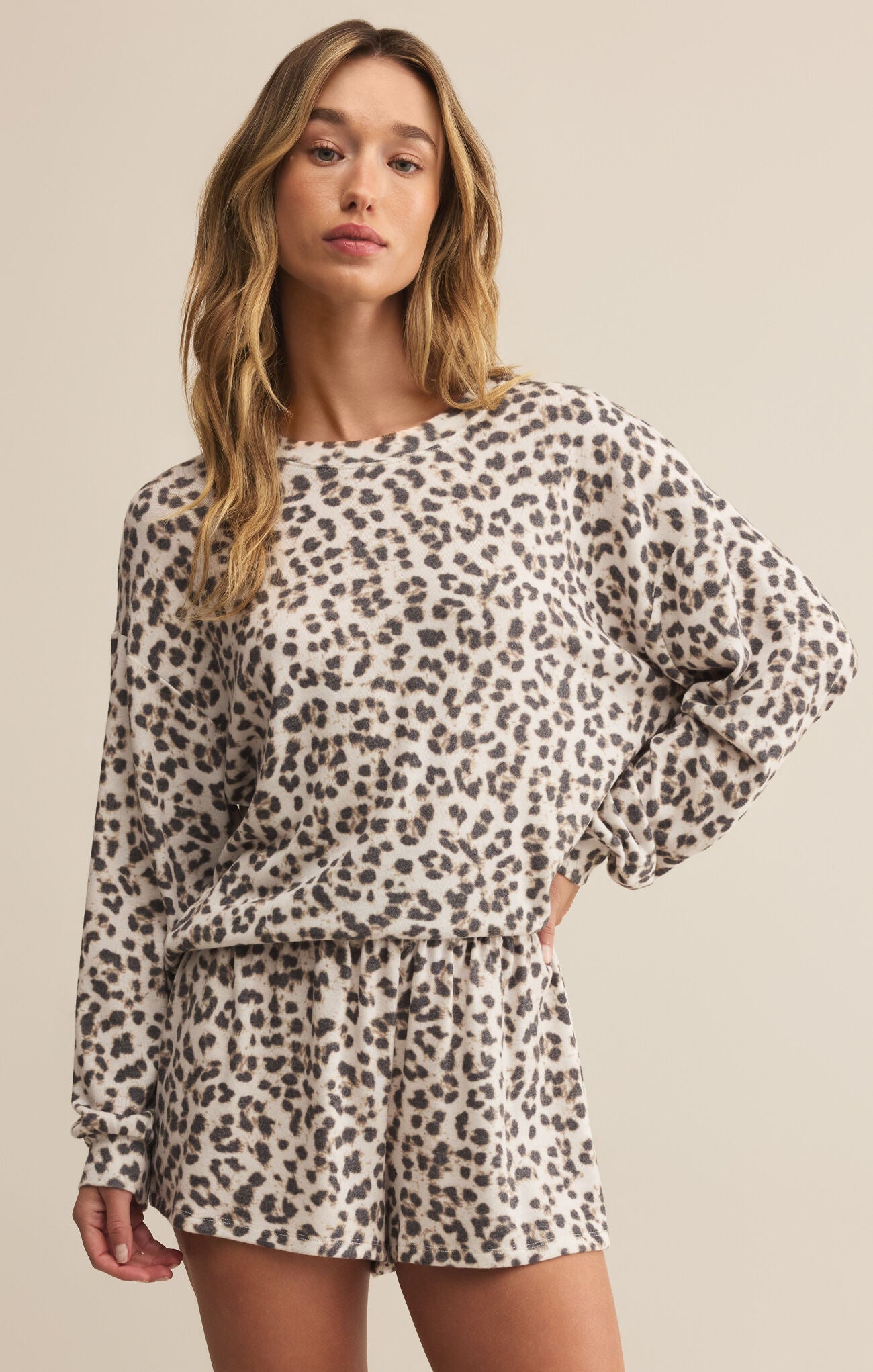 A female model wearing a leopard print long sleeve top with a relaxed fit and shorts, standing against a neutral background.