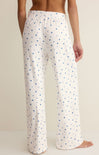 White pajama pants with blue star pattern worn by a person on a beige background