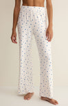 White pajama pants with blue star pattern worn by a person on a beige background
