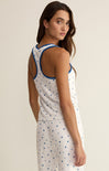 Woman wearing a white sleeveless dress with blue accents on a beige background