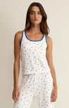 Woman wearing a white sleeveless top with blue star pattern and matching pants on a beige background